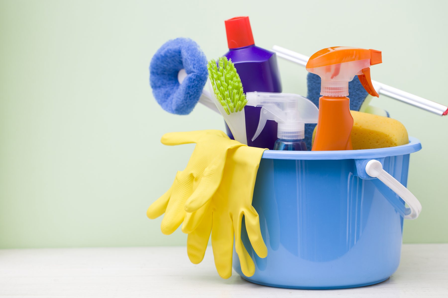 Cleaning supplies in a bucket on a wooden floor